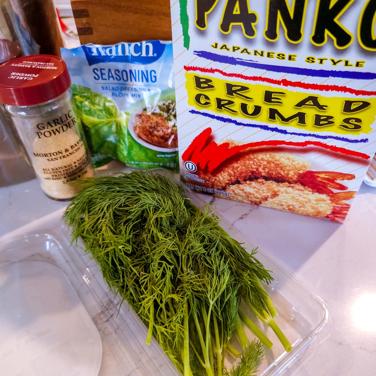 Panko, flour, dill, and ranch seasoning on a countertop.