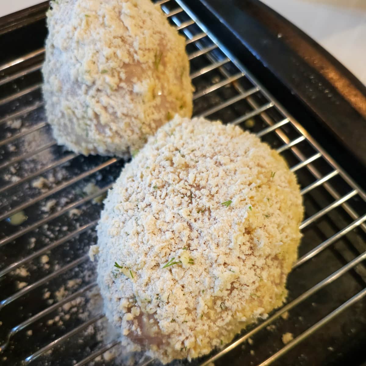 Breaded chicken Kiev with fresh herbs on a wire rack.