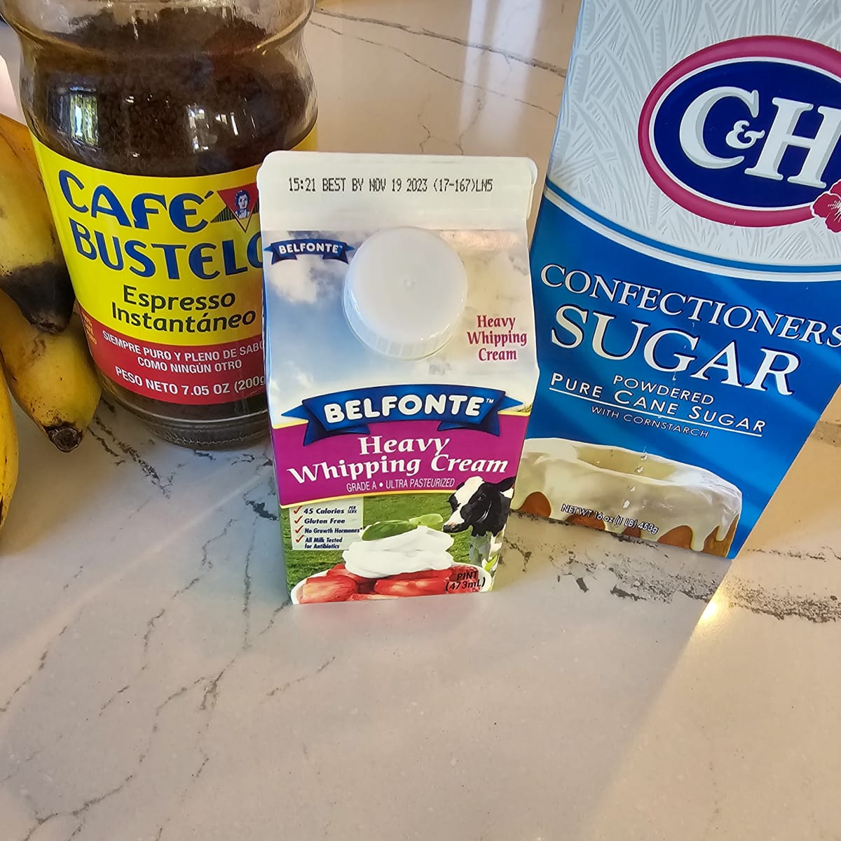 Heavy cream, powdered sugar, and instant espresso on a counter.