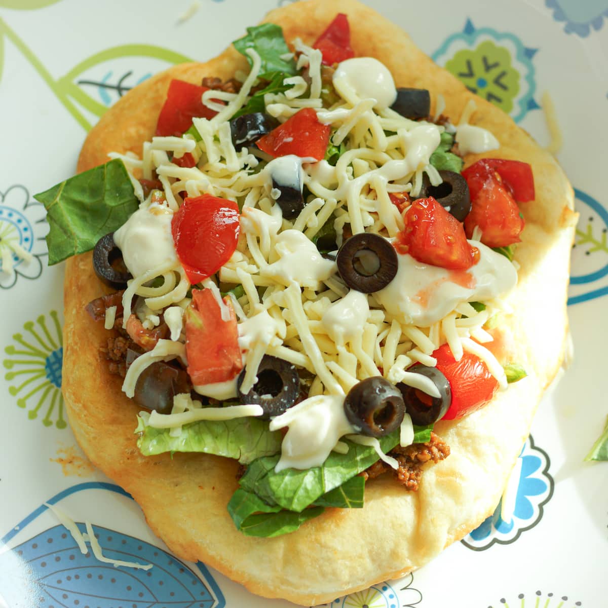 Navajo fry bread taco topped with seasoned beef, black olives, tomato, cheese, lettuce and sour cream.