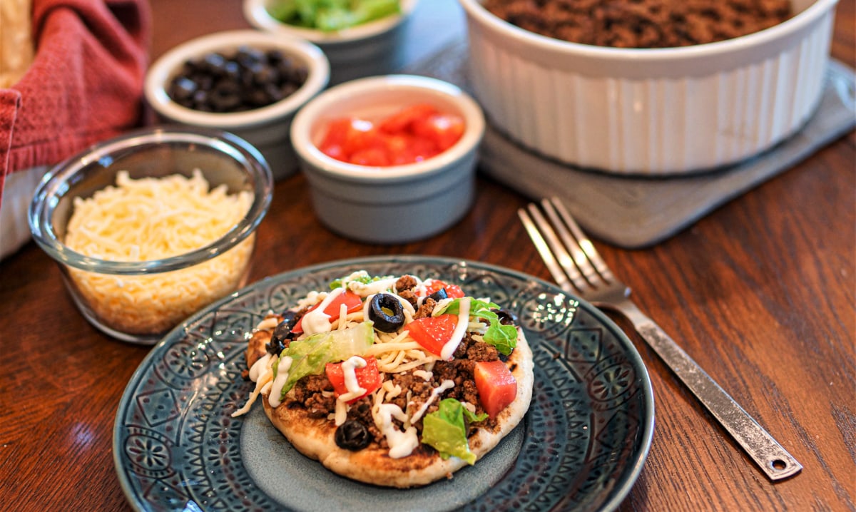 Bison Indian tacos on a table with toppings.