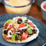 Indian fry bread taco on a table with taco toppings.