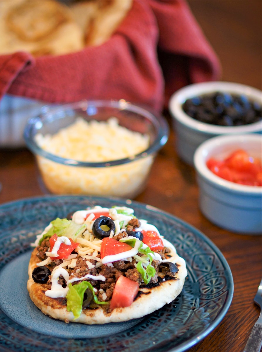 Navajo fry bread taco with assorted toppings on a table.