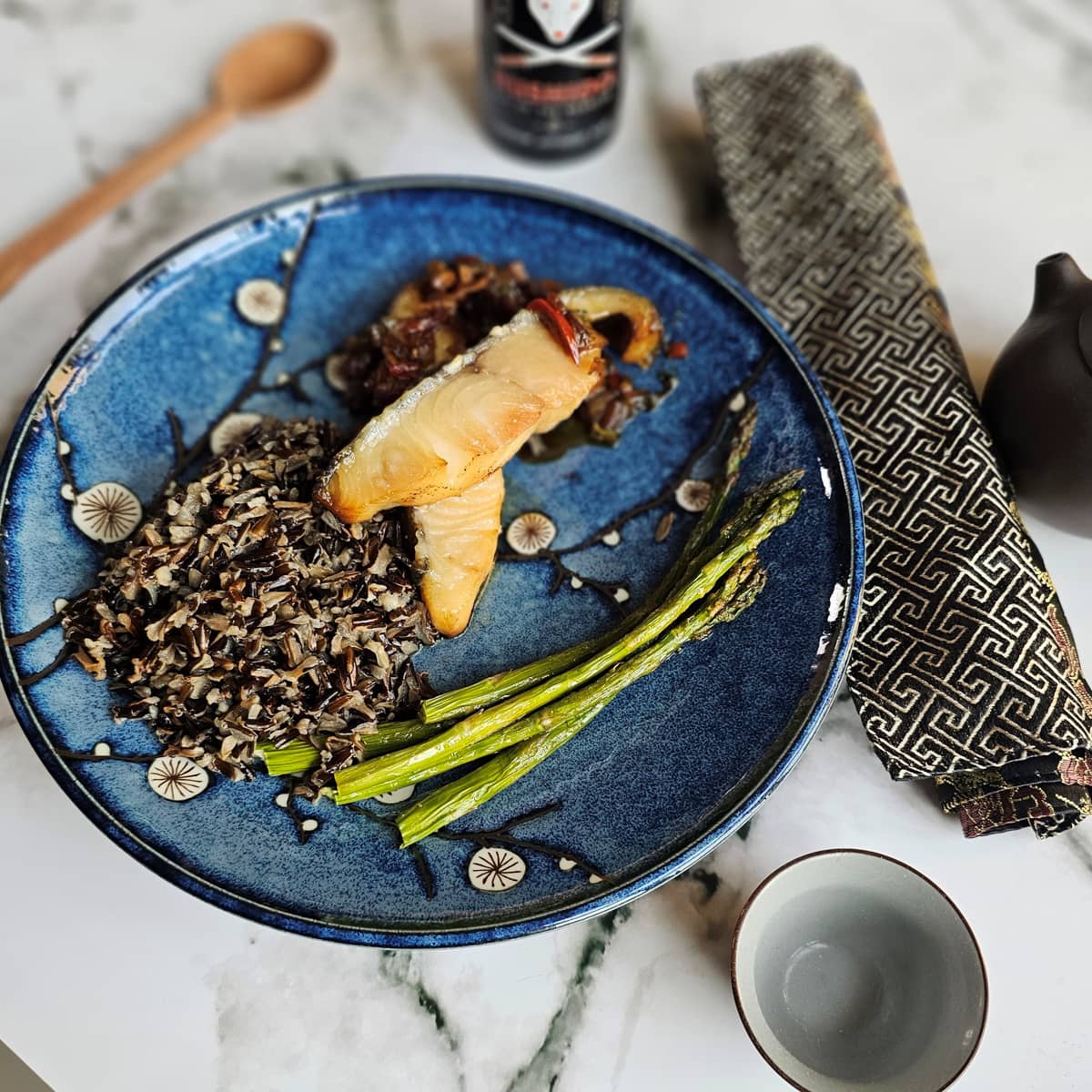 Decorative plate with black rice and smoked miso butterfish.