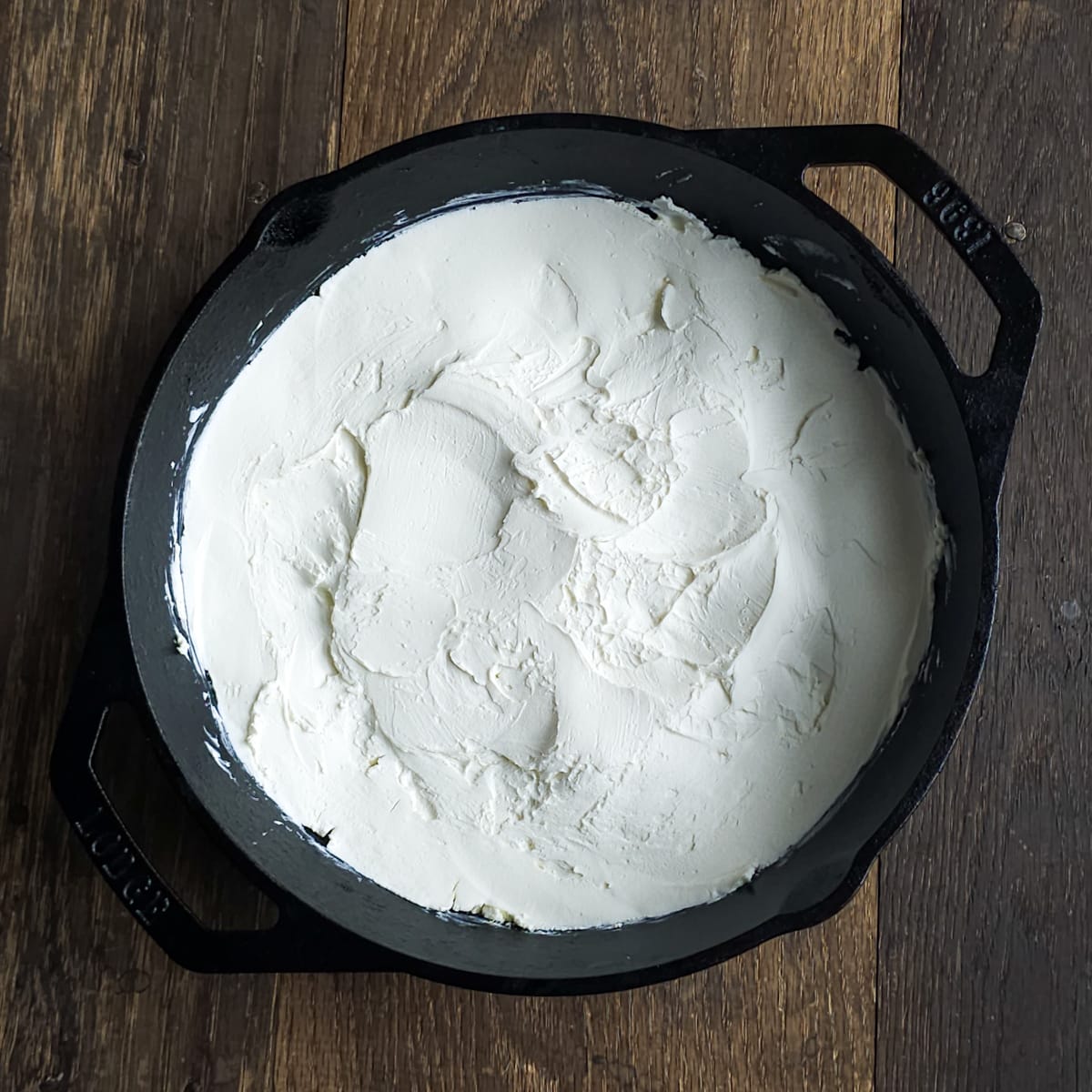 Cream cheese spread in the bottom of a cast iron pan.