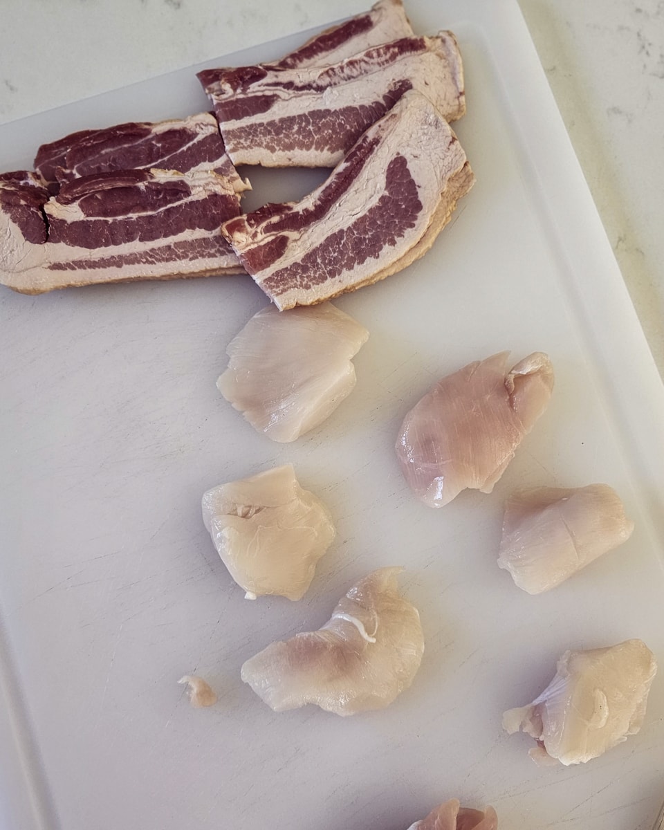 Cutting board with halibut cheeks and bacon.
