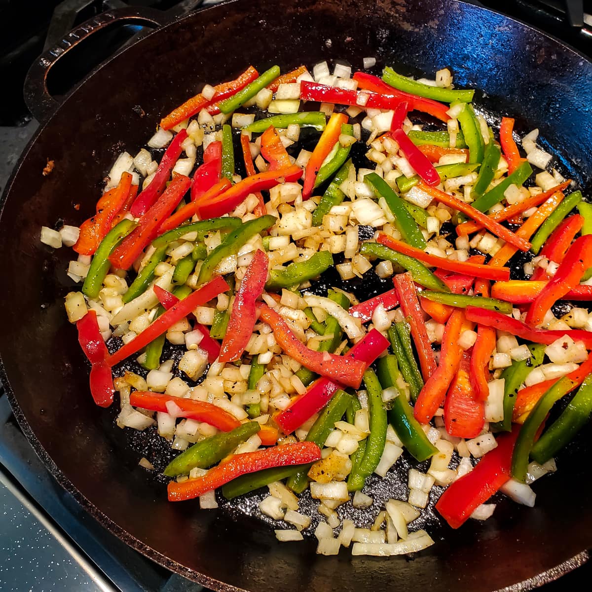 Veggies cooking in a cast iron skillet.