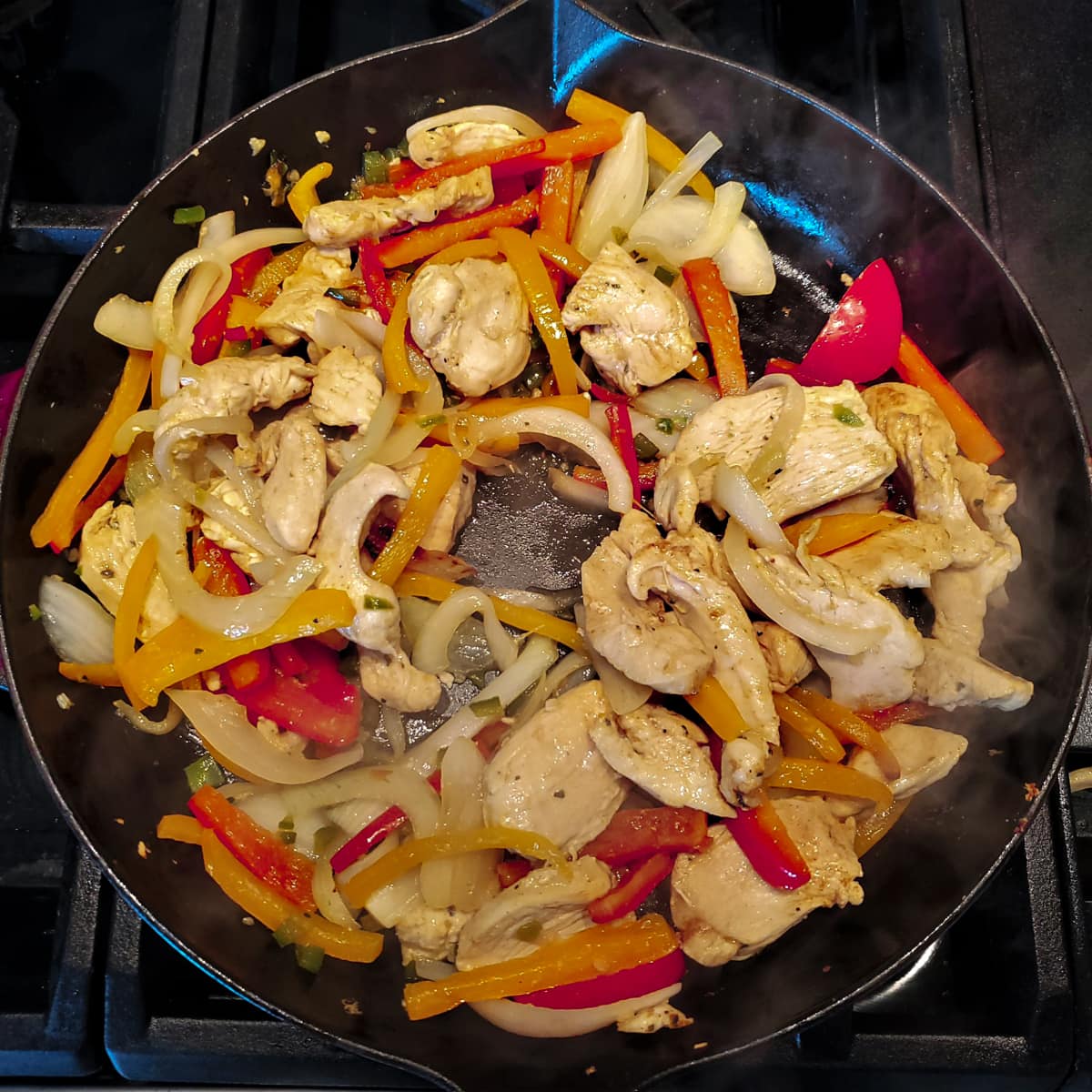Chicken and peppers in a cast iron skillet.