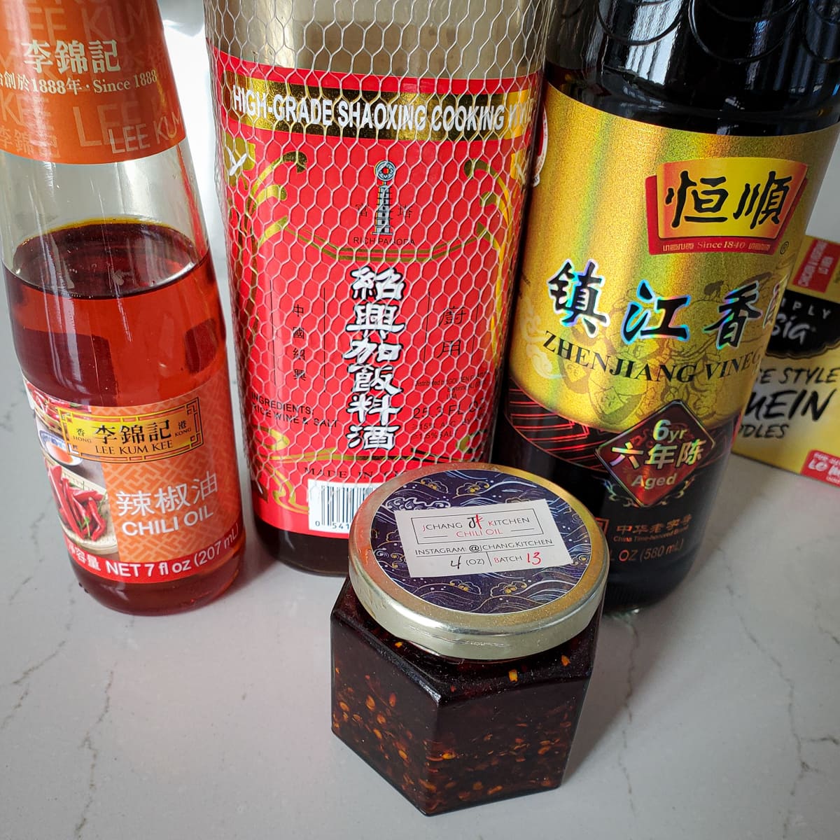 Chili oil, chili paste, Chinese vinegar, and Chinese cooking wine on a countertop.