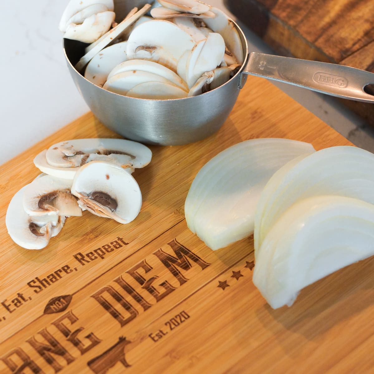 Cutting board with sliced mushrooms and onion.