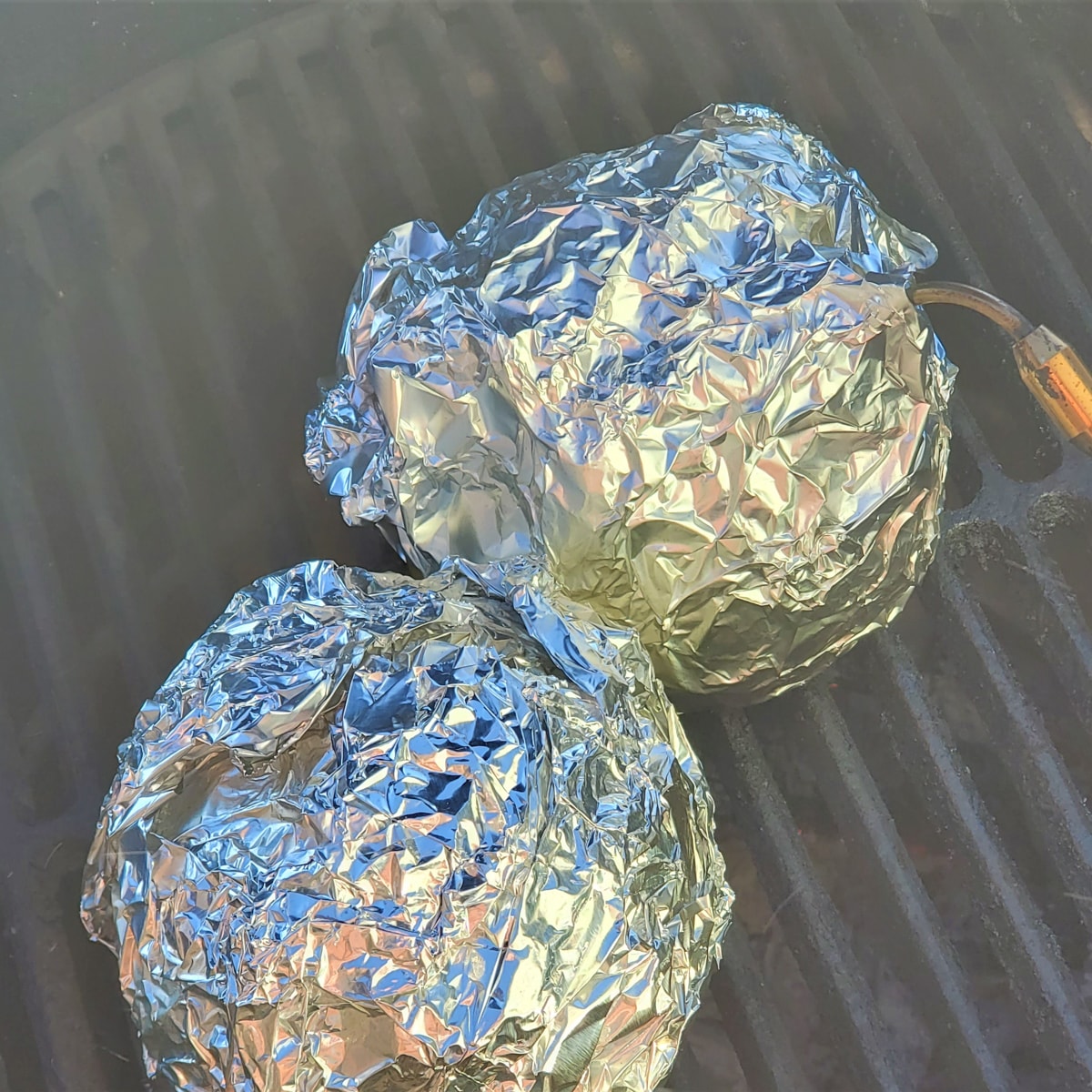 Stuffed coconuts wrapped in foil, roasting on a Big Green Egg.