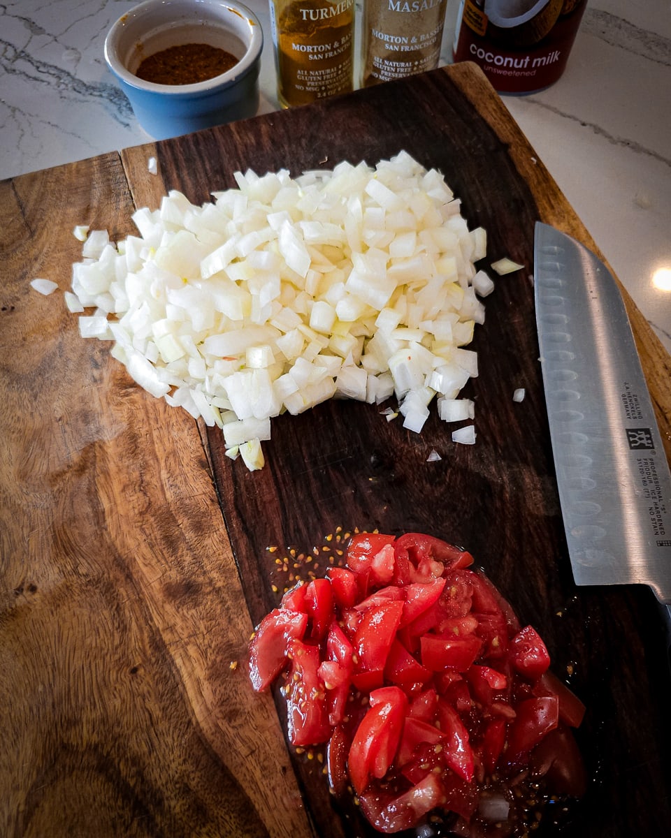 Diced onion and diced tomato on a cutting board.