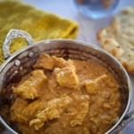 Bowl of Northern Indian Butter Chicken served with naan bread.