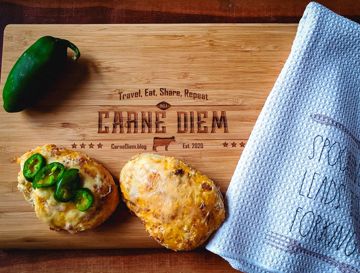 Twice baked potatoes on a cutting board reading Carne Diem: Travel, Eat, Share, Repeat.
