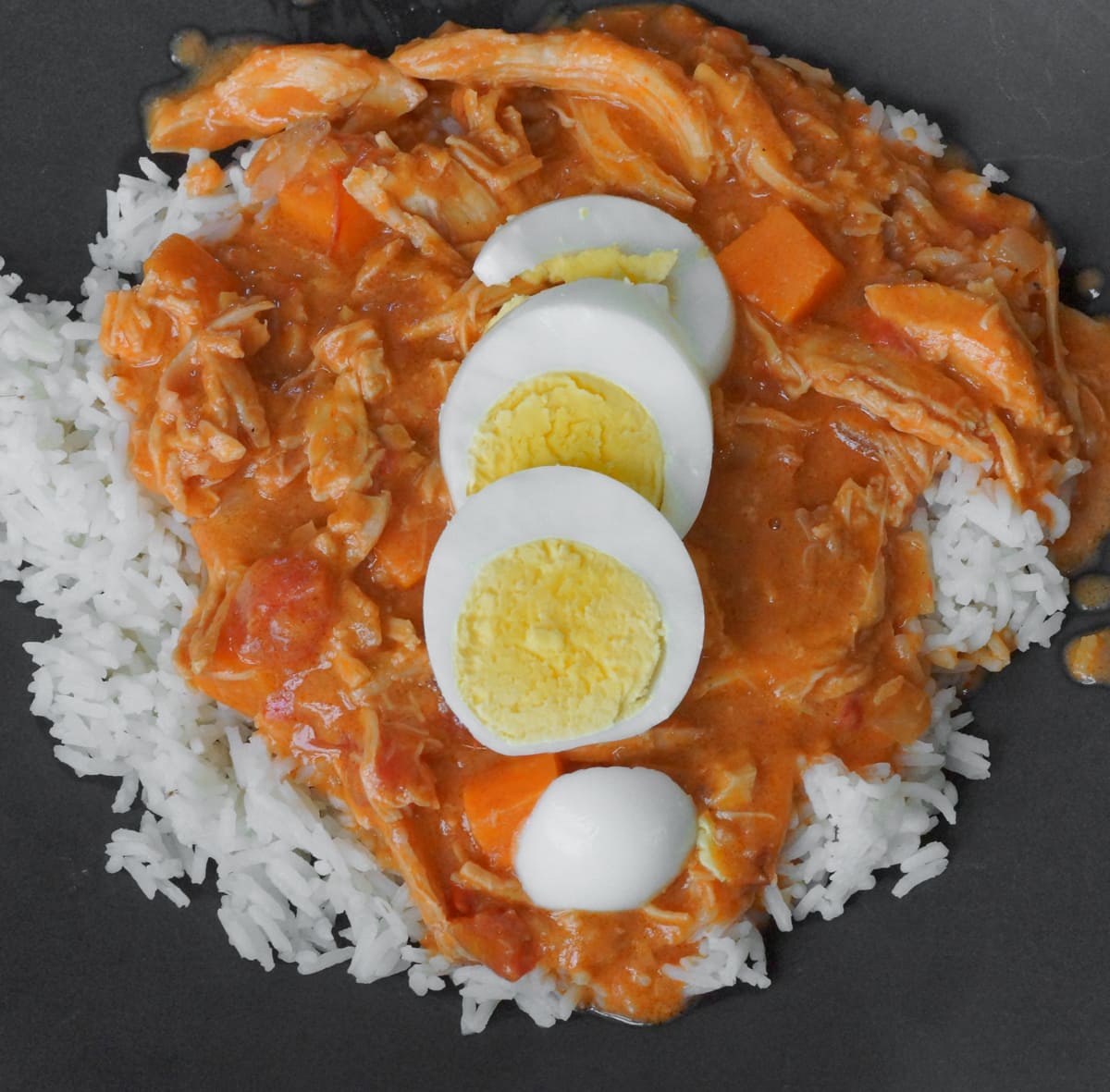 Groundnut stew served with rice and topped with slices of hardboiled egg.