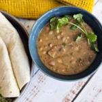 Bowl of homemade charro beans with warm tortillas.