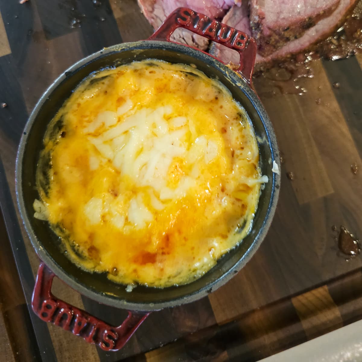 Serving of cheesy corn with smoked ham in a cocotte.
