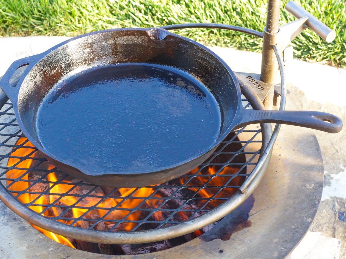 Cast iron skillet heating over a firepit.
