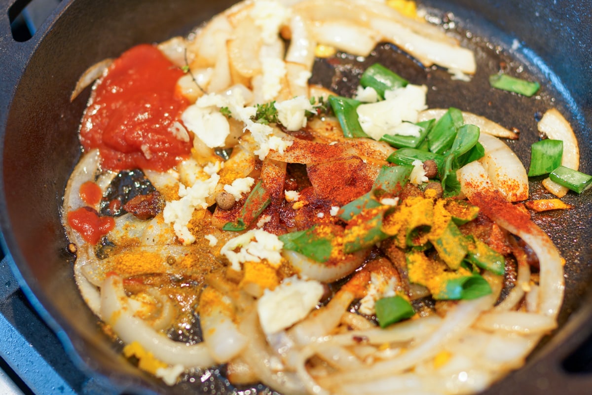 Seasoning added to a cast iron pan of veggies.