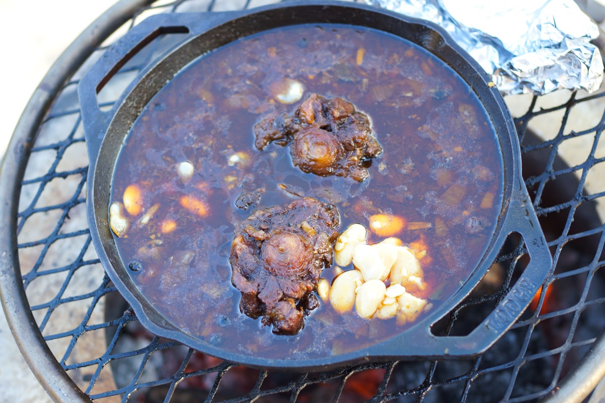 Caribbean oxtail stew cooking over a live fire.