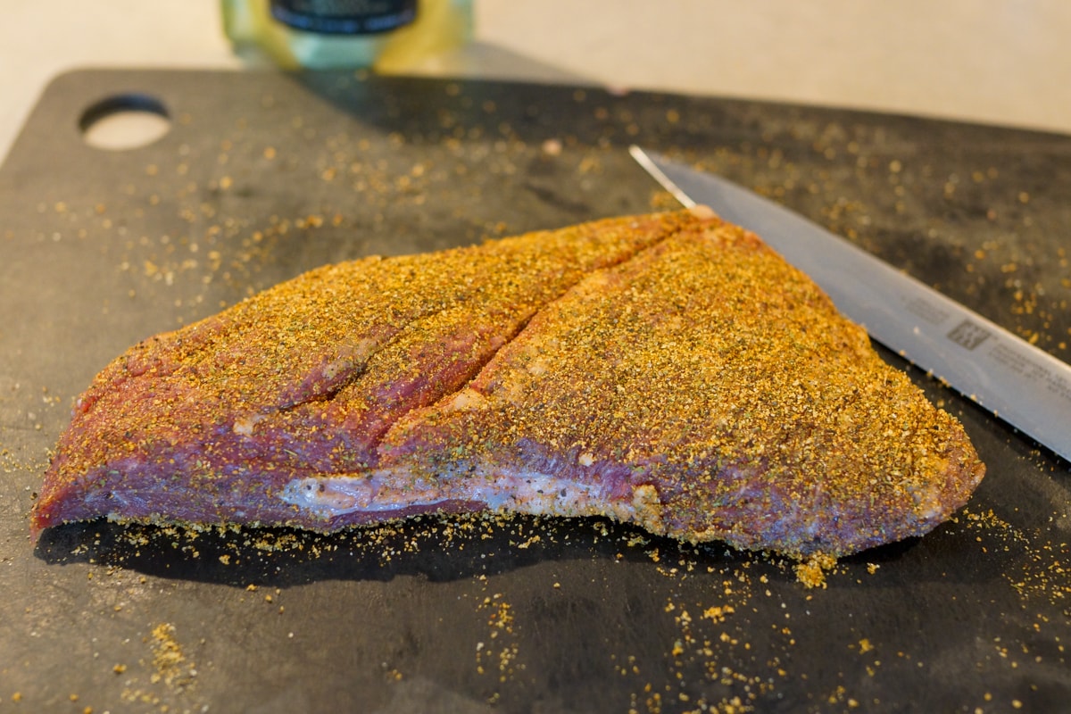 Seasoned tri tip roast with a shallow cut marking the grain of the meat.