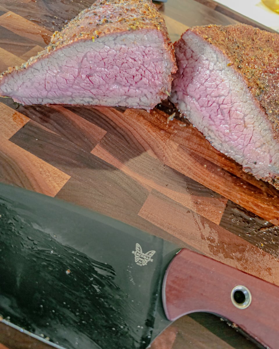 Grilled Santa Maria tri tip roast cut in half on a cutting board.