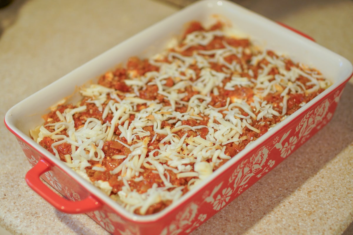 Shredded cheese on top of uncooked lasagna.
