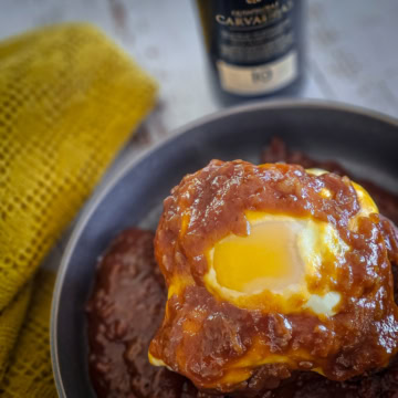 A traditional francesinha sandwich from Portugal, served smothered with beer sauce and topped with a fried egg and melted cheese.