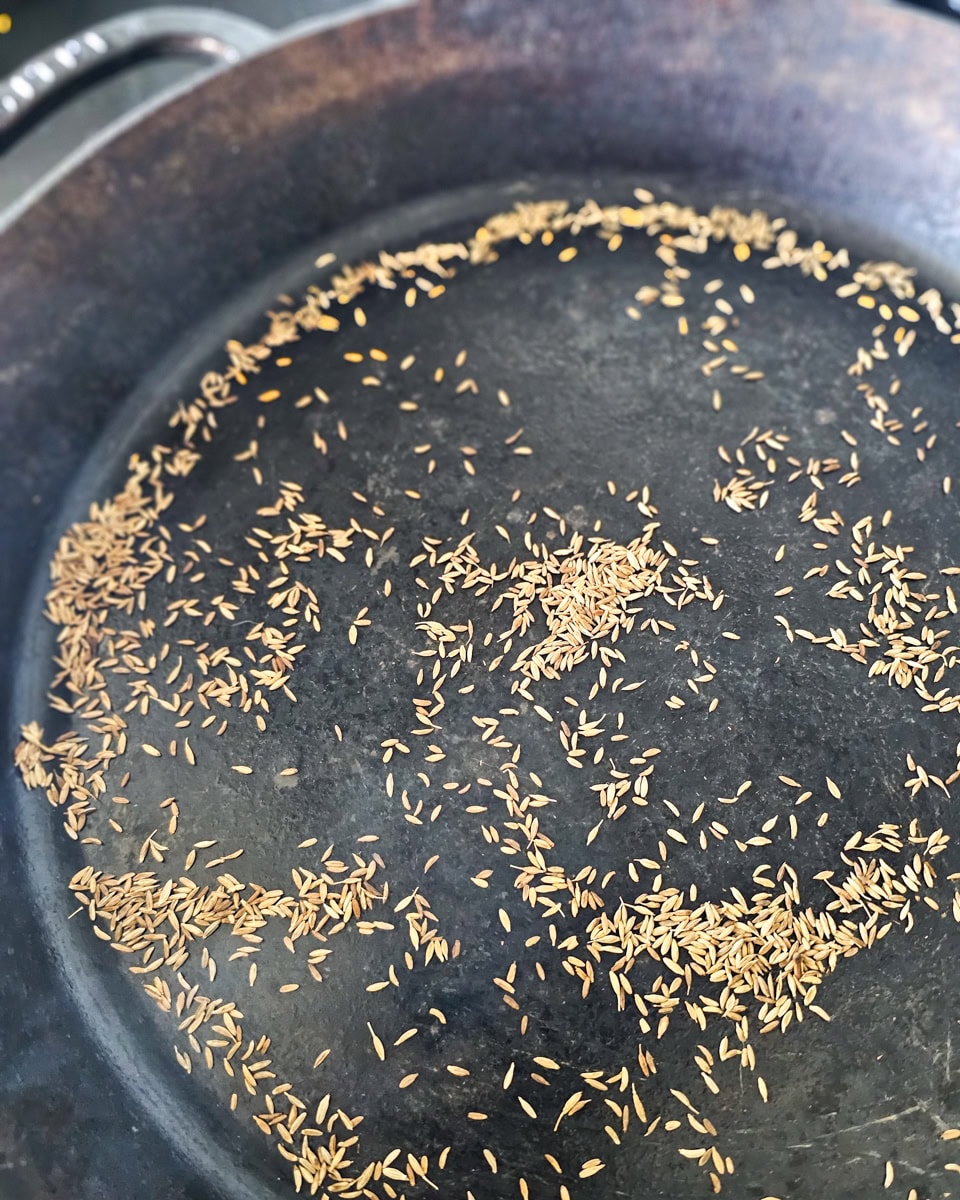 Cumin toasting in a pan.