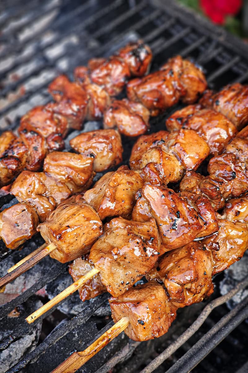 Cooking Filipino pork skewers on a BBQ grill over charcoal.