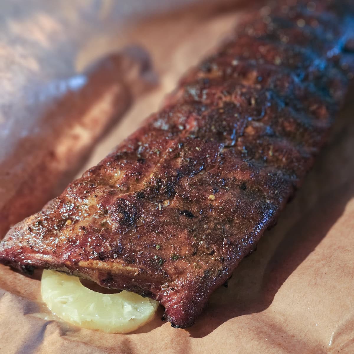 Smoked ribs on butcher paper with pineapple slices.