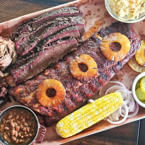 A tray of al pastor flavored ribs, brisket, corn, and beans.