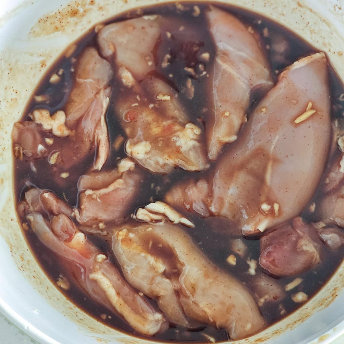 Chicken thighs in a bowl of Huli Huli marinade.