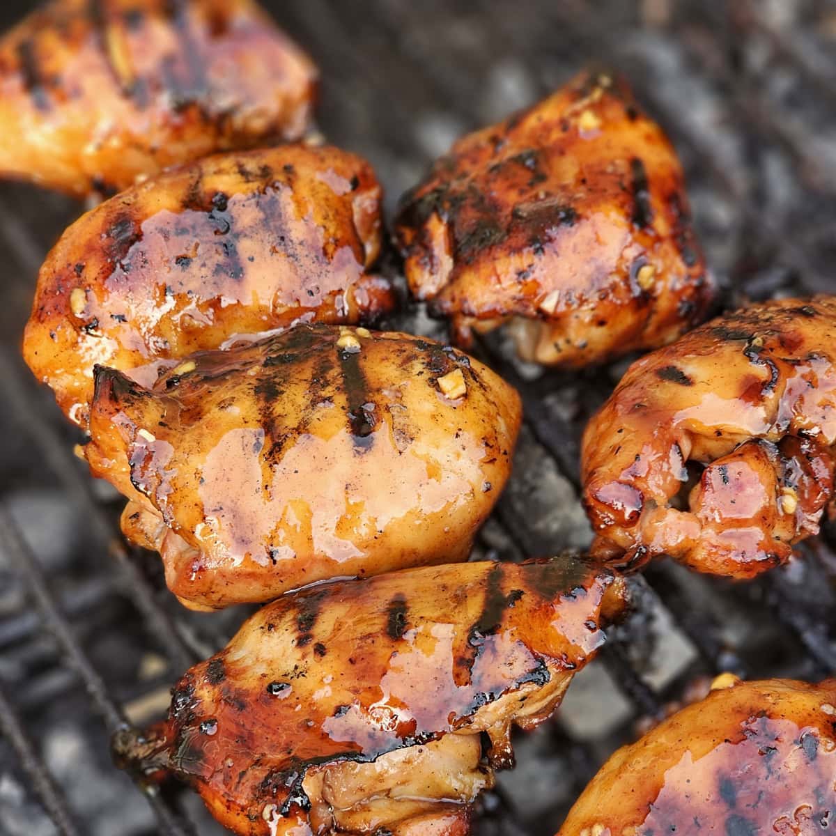 Charcoal grilled Hawaiian Huli Huli chicken cooking on a BBQ grill.