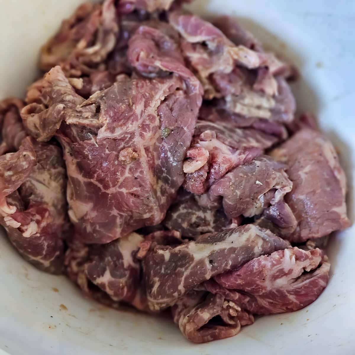 Thinly sliced steak marinating in carne asada seasoning.