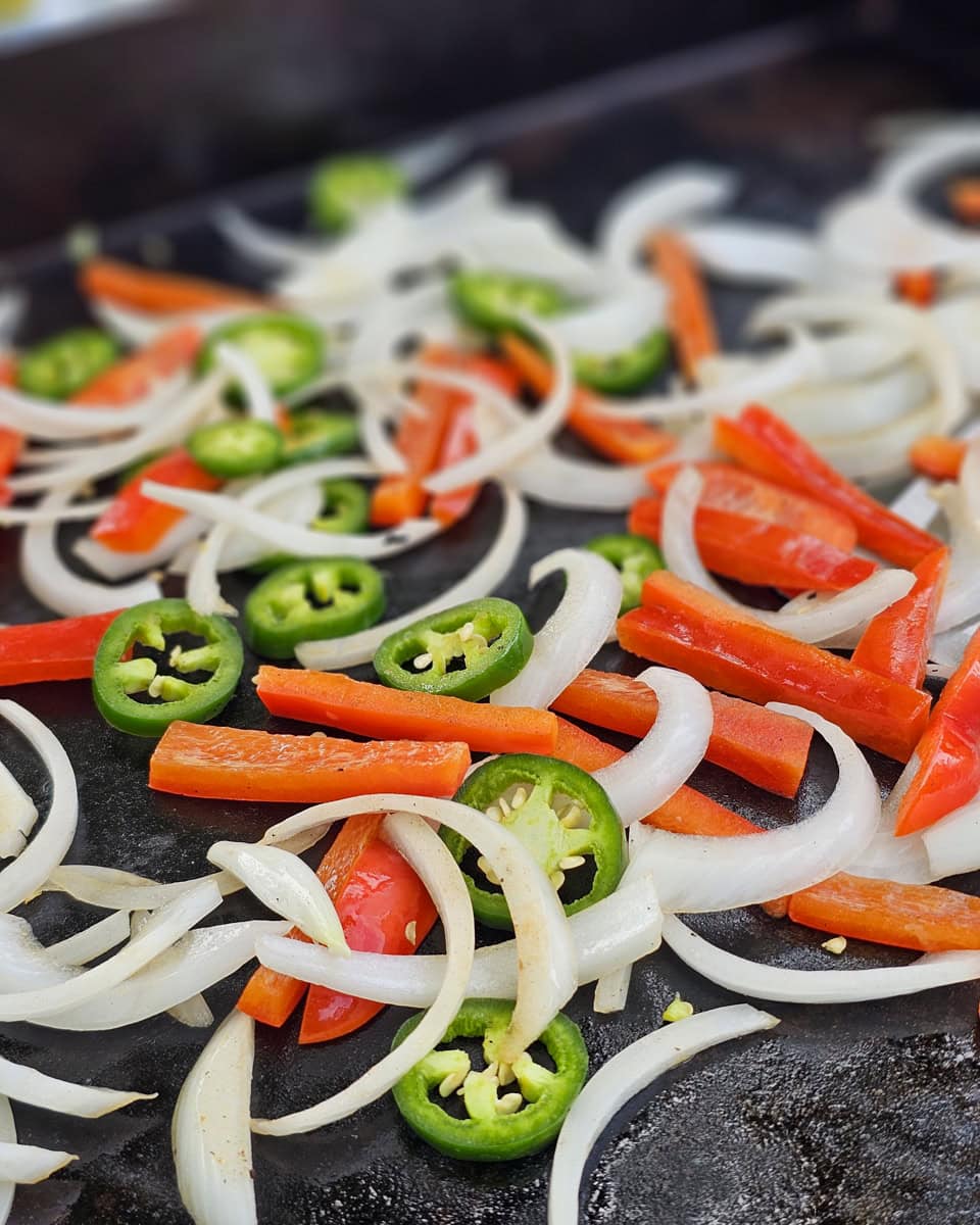 Peppers and onions cooking on a Blackstone griddle.