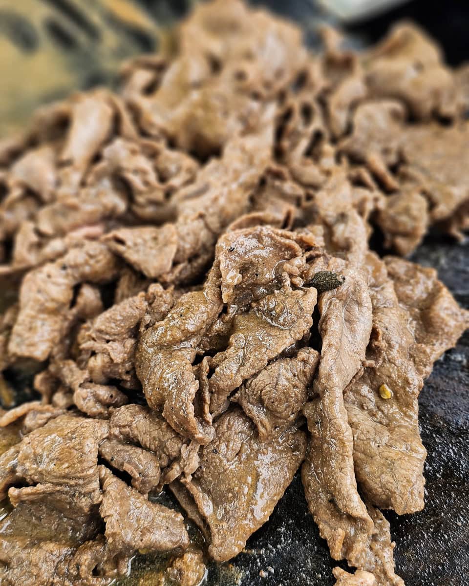 Carne asada seasoned steak cooking on a Blackstone.