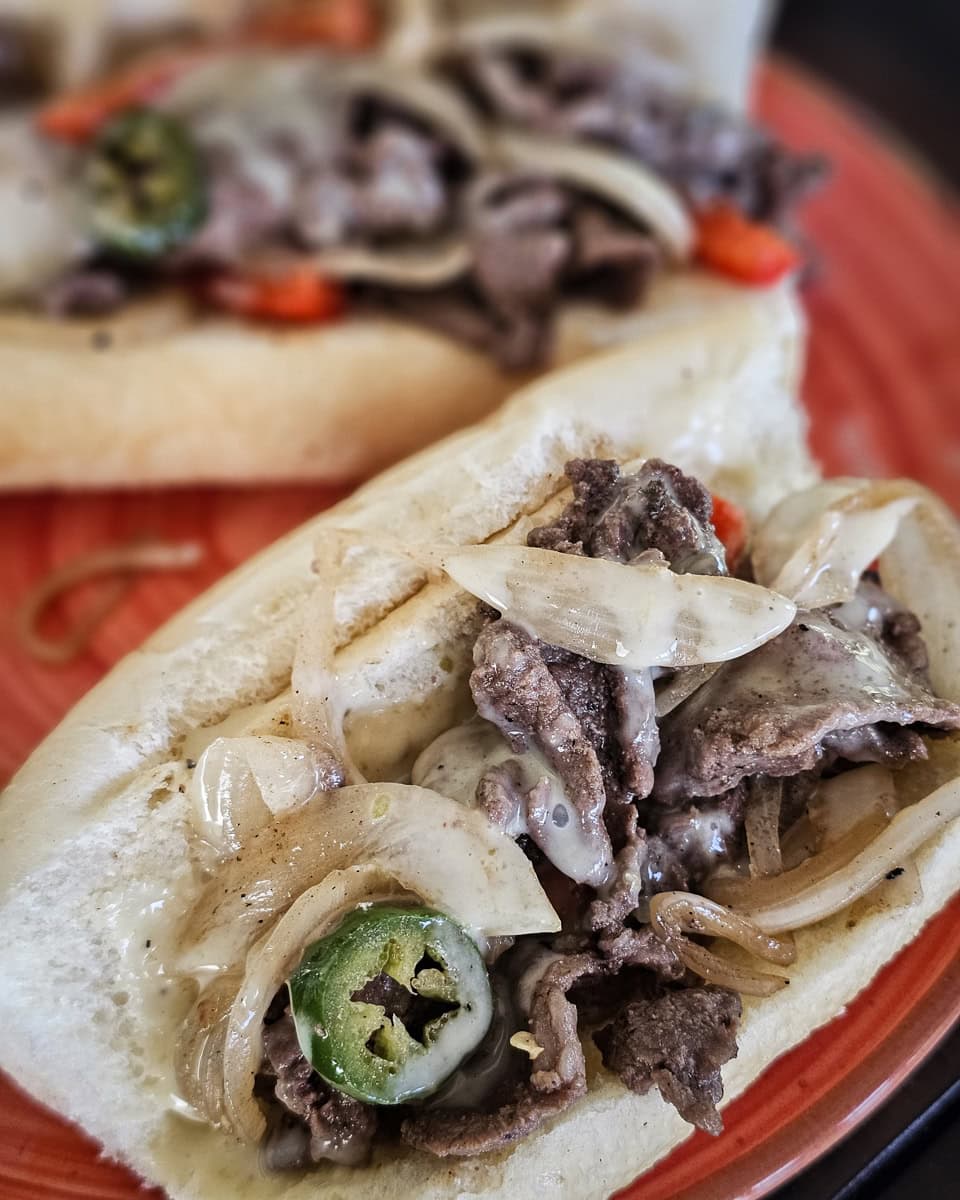 Carne asada cheesesteak hoagie with queso, onions, and jalapenos.