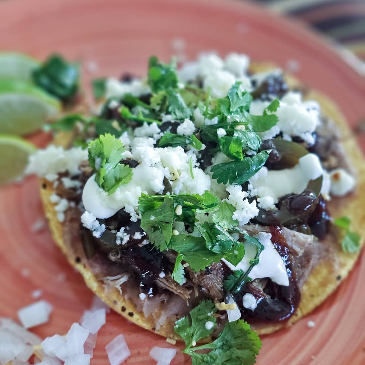 Pulled pork tostadas with BBQ sauce, sour cream, beans, and candied jalapenos.