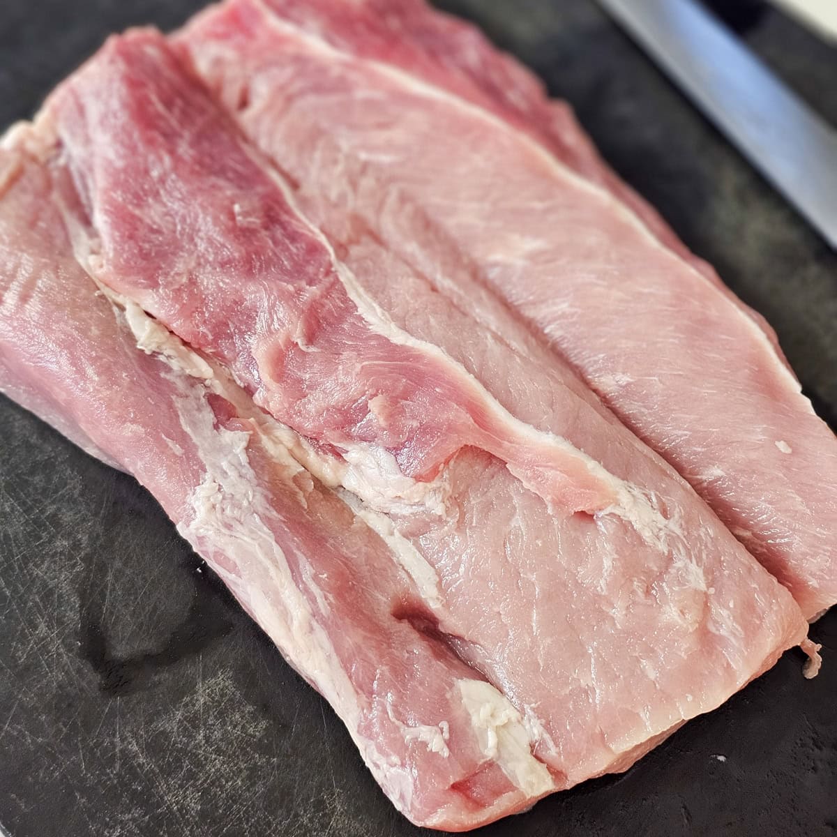 3 pound pork loin filleted open, on a cutting board.