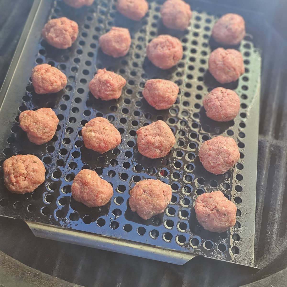 Meatballs cooking on a grill.