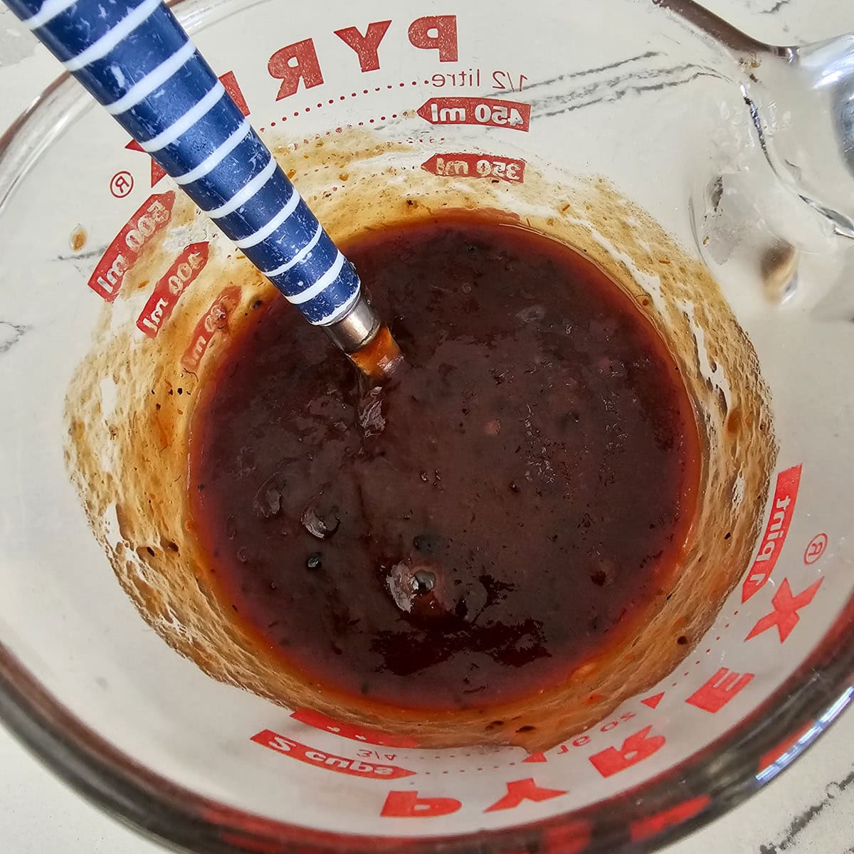 Mixing together a sweet and savory meatball glaze.