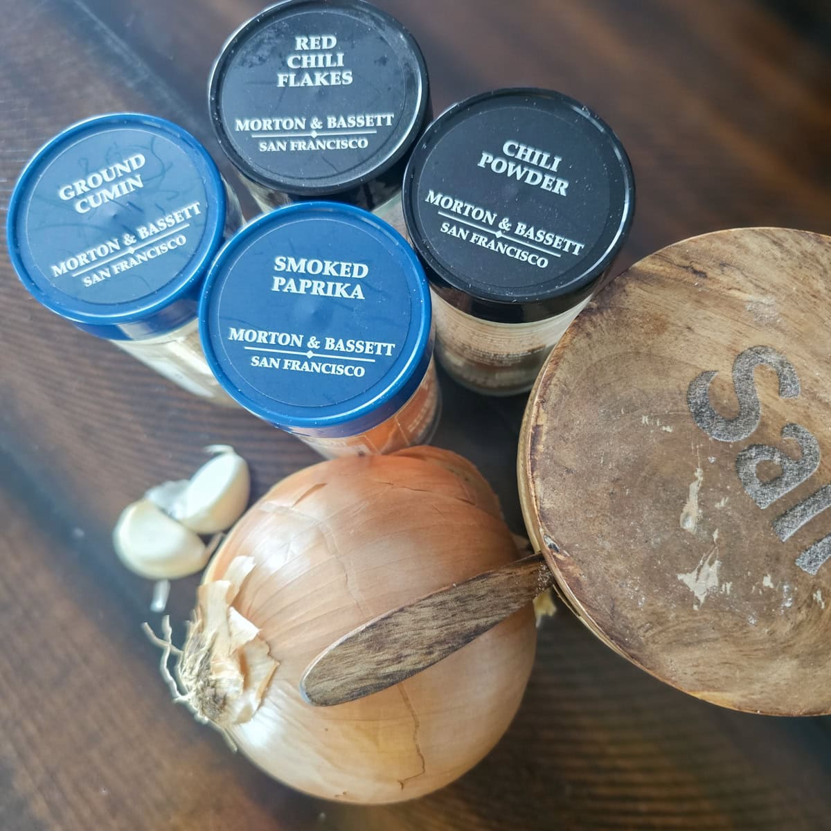 Assorted seasonings and spices, salt, and a yellow onion.