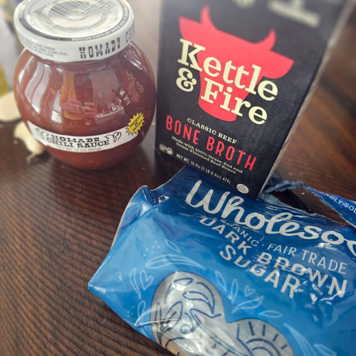 Brown sugar, chili sauce, and beef broth on a table.