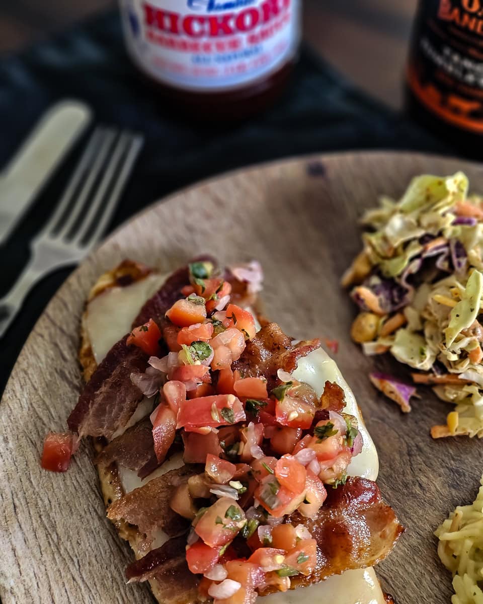 Plate of monterey chicken topped with cheese, bacon, pico de gallo, and BBQ sauce.