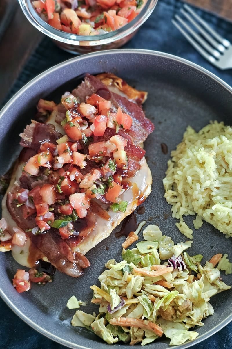 Plate with homemade Monterey chicken, cooked on a Blackstone, topped with bacon and pico de gallo.