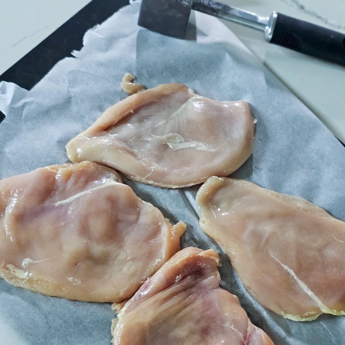 Four chicken breasts that have been pounded thinner.