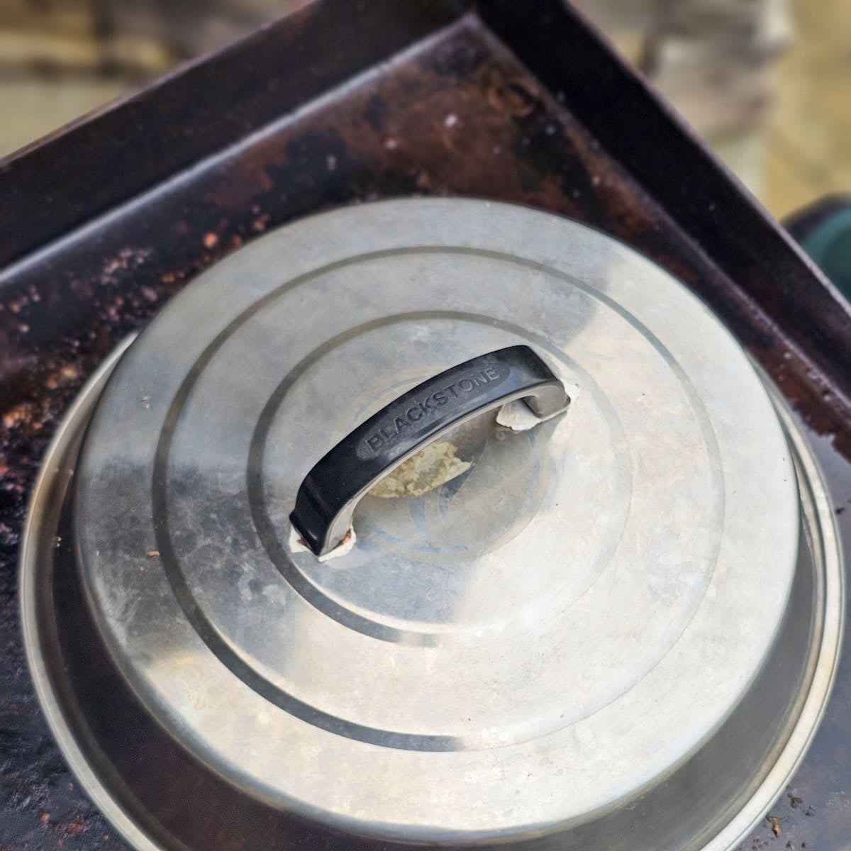 Using a dome lid to melt cheese onto of chicken breasts, on a flat top grill.