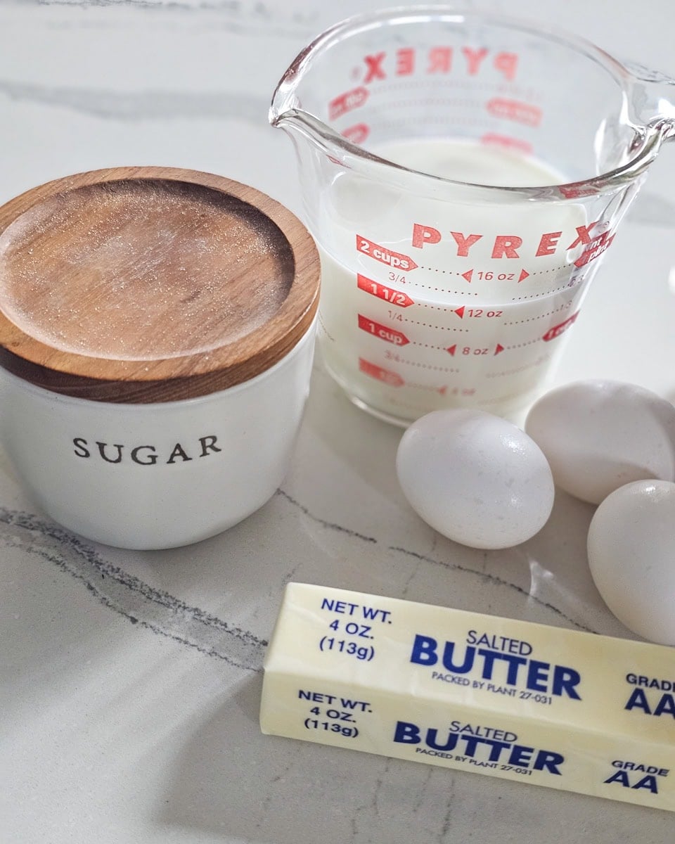 Sugar, Milk, Butter, and eggs on a countertop.