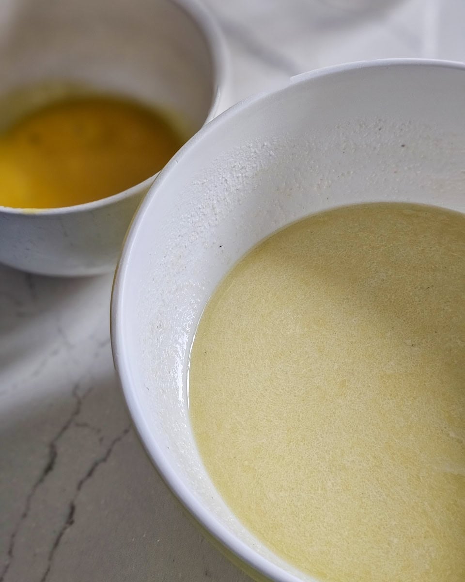 Beaten eggs in a bowl, and corn meal in another bowl.